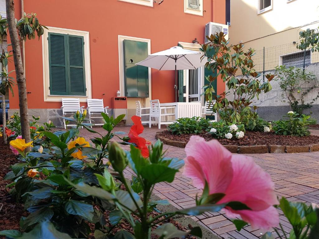 a patio with an umbrella and flowers in front of a building at Villetta Volta in Rapallo
