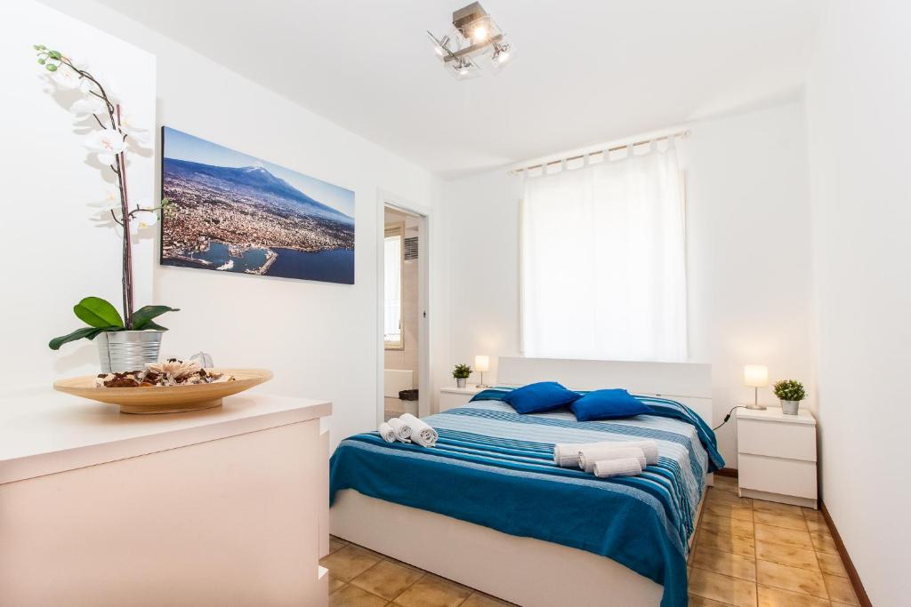 - une chambre blanche avec un lit bleu et une fenêtre dans l'établissement Sicilia Etna Mare, à Mascali