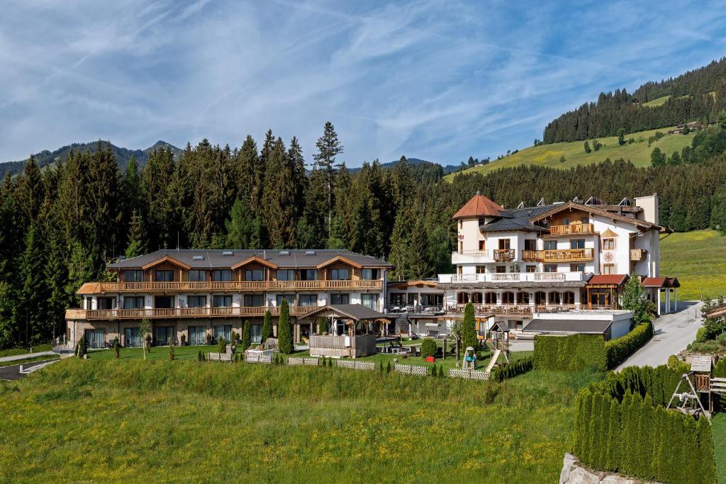 um grande hotel numa colina com um campo verde em Leamwirt em Hopfgarten im Brixental