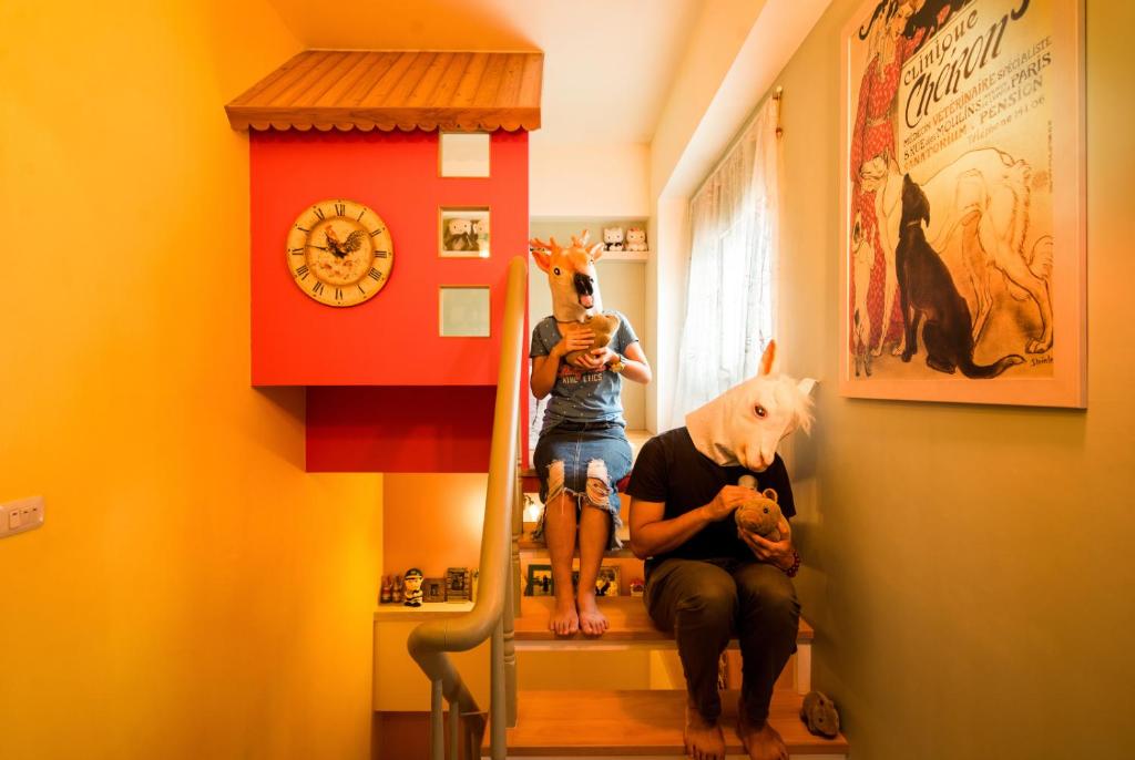 a woman sitting on the stairs in a hallway with a clock at Happiness B&amp;B in Luodong