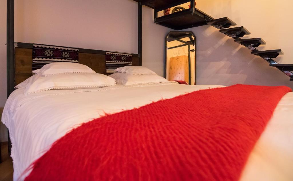a white bed with a red blanket on it at Folkloric Loft - Sibiul vechi in Sibiu