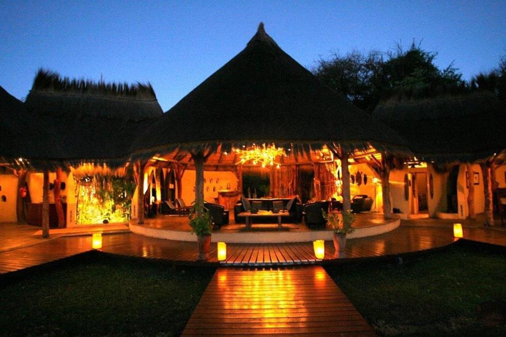 ein Haus mit einer Terrasse in der Nacht mit Lichtern in der Unterkunft Camp Kwando in Kongola