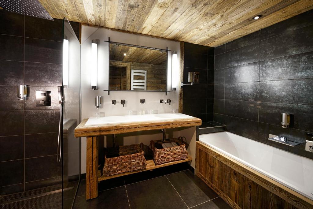 a bathroom with a sink and a tub and a mirror at Chalet-Hôtel La Marmotte, La Tapiaz & SPA, The Originals Relais in Les Gets