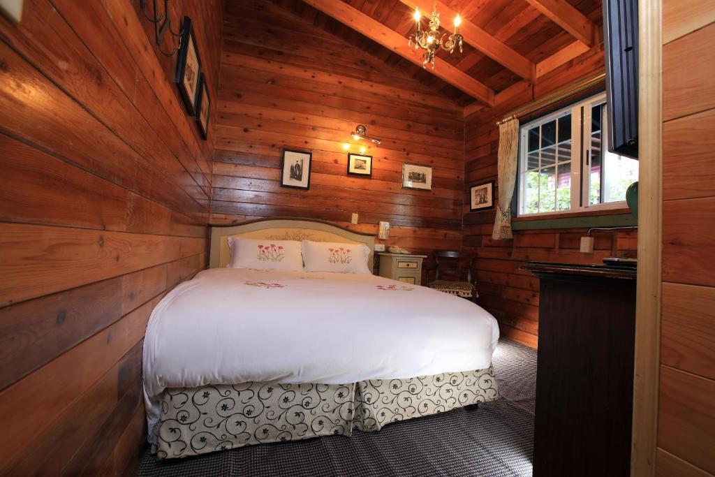 a bedroom with a bed in a wooden cabin at Cingjing Hanging Garden &amp; Resort in Ren&#39;ai