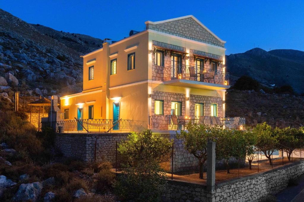 a large yellow house with lights on at Royal Villa Pedi in Symi