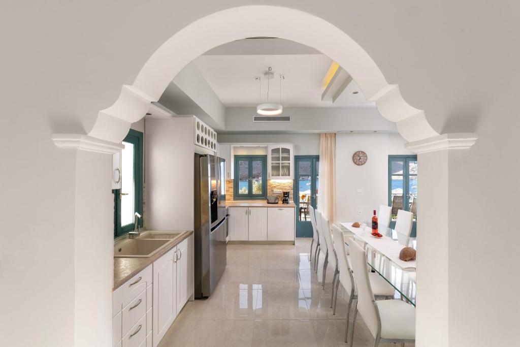 an archway in a kitchen with white cabinets and chairs at Royal Villa Pedi in Symi