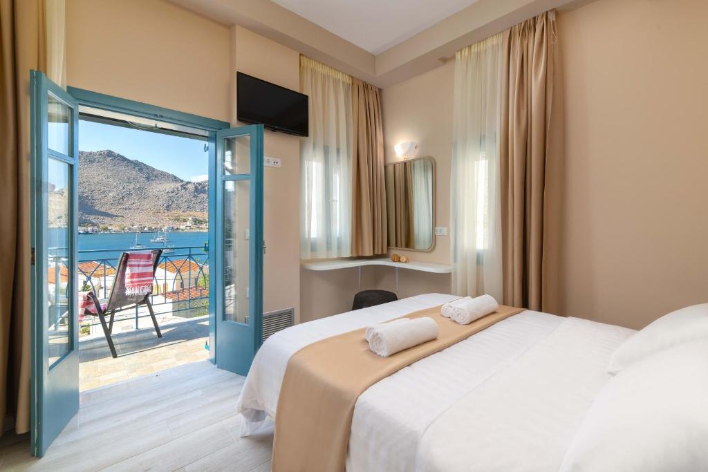 a bedroom with a bed and a balcony with a view at Royal Villa Pedi in Symi
