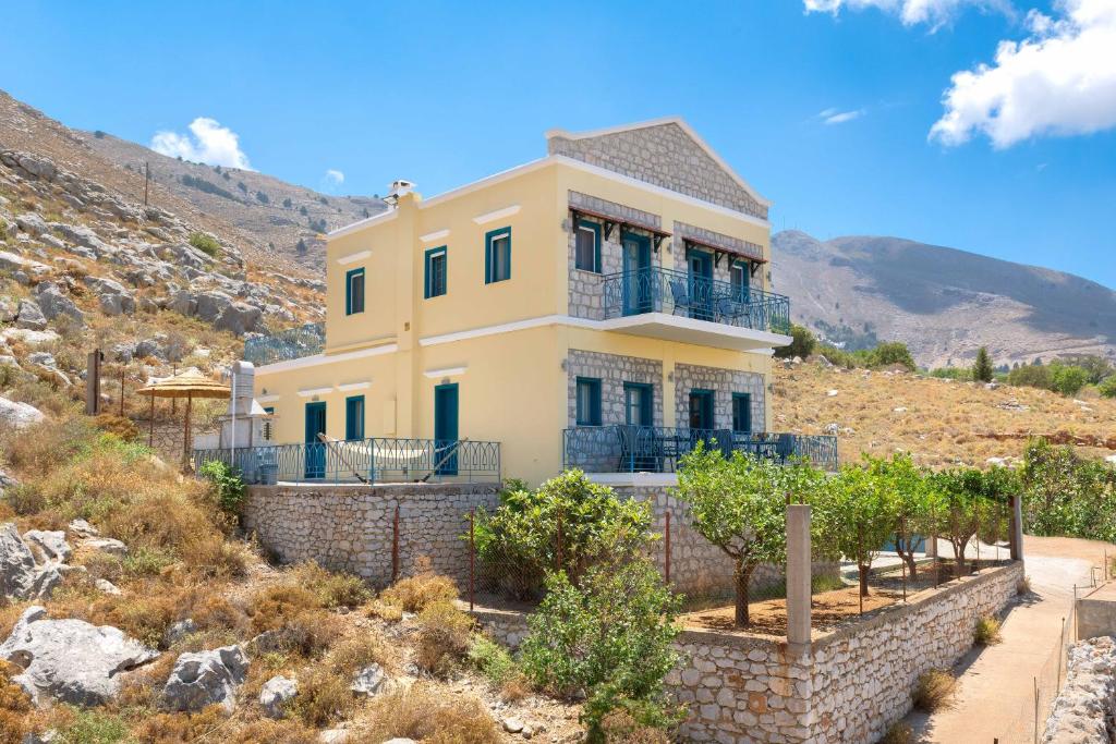 a large yellow house on top of a hill at Royal Villa Pedi in Symi