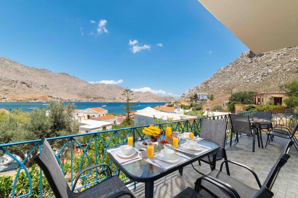 a table on a balcony with a view of the water at Royal Villa Pedi in Symi