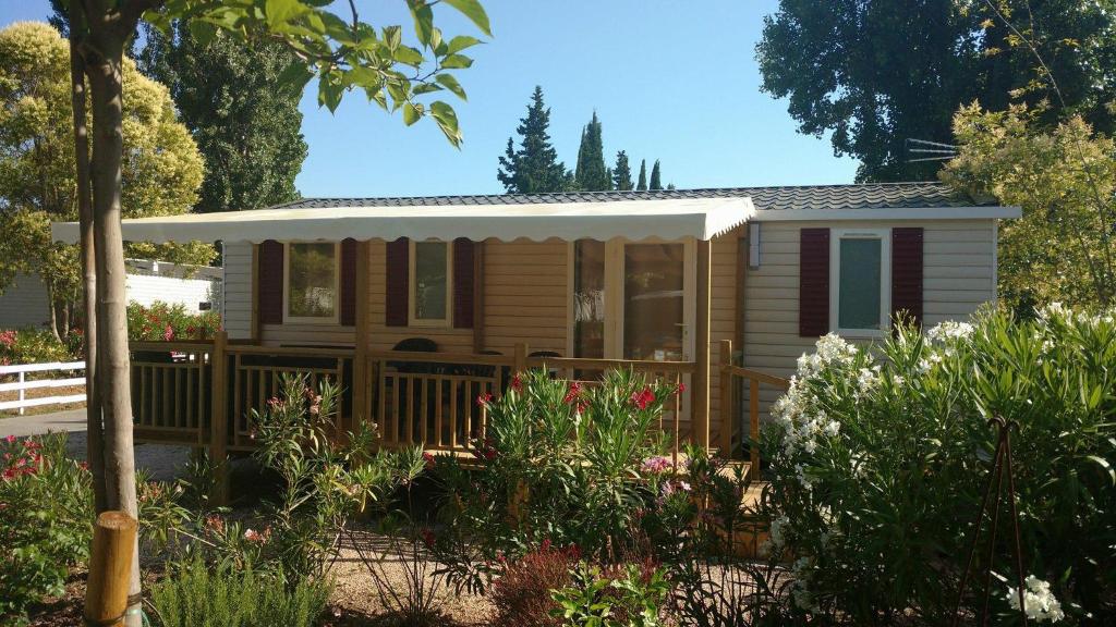 a tiny house in a garden with flowers at Best Confort Mobile Home 2 chambres et salon in Fréjus