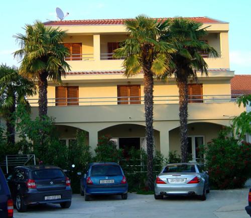 three cars parked in front of a building with palm trees at Apartments & rooms Ana Sukosan in Sukošan