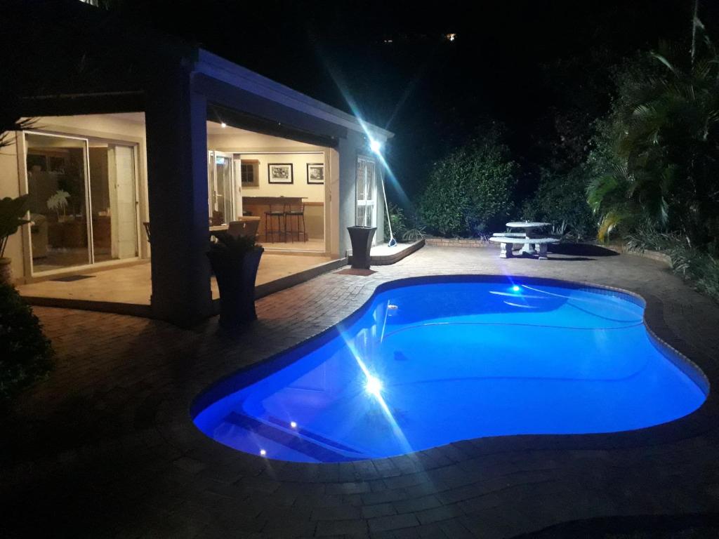 a blue swimming pool in a yard at night at Bella Vista Guest House in Durban
