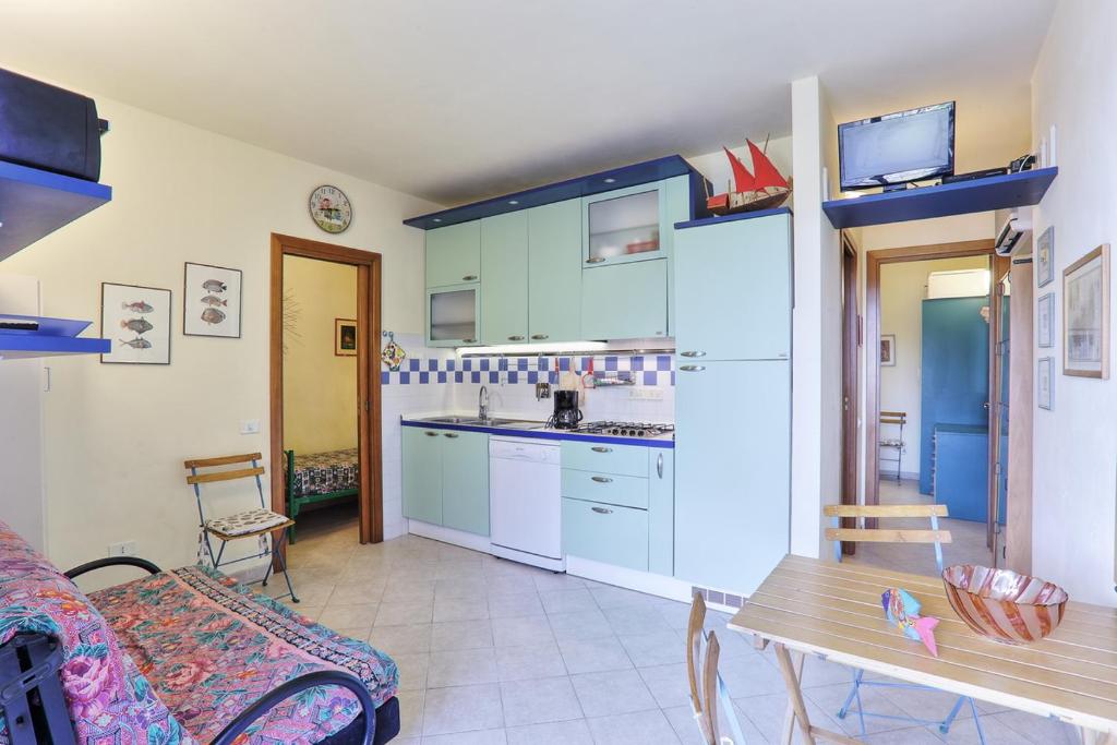 a kitchen with blue cabinets and a table and a couch at Bouganville in Capoliveri