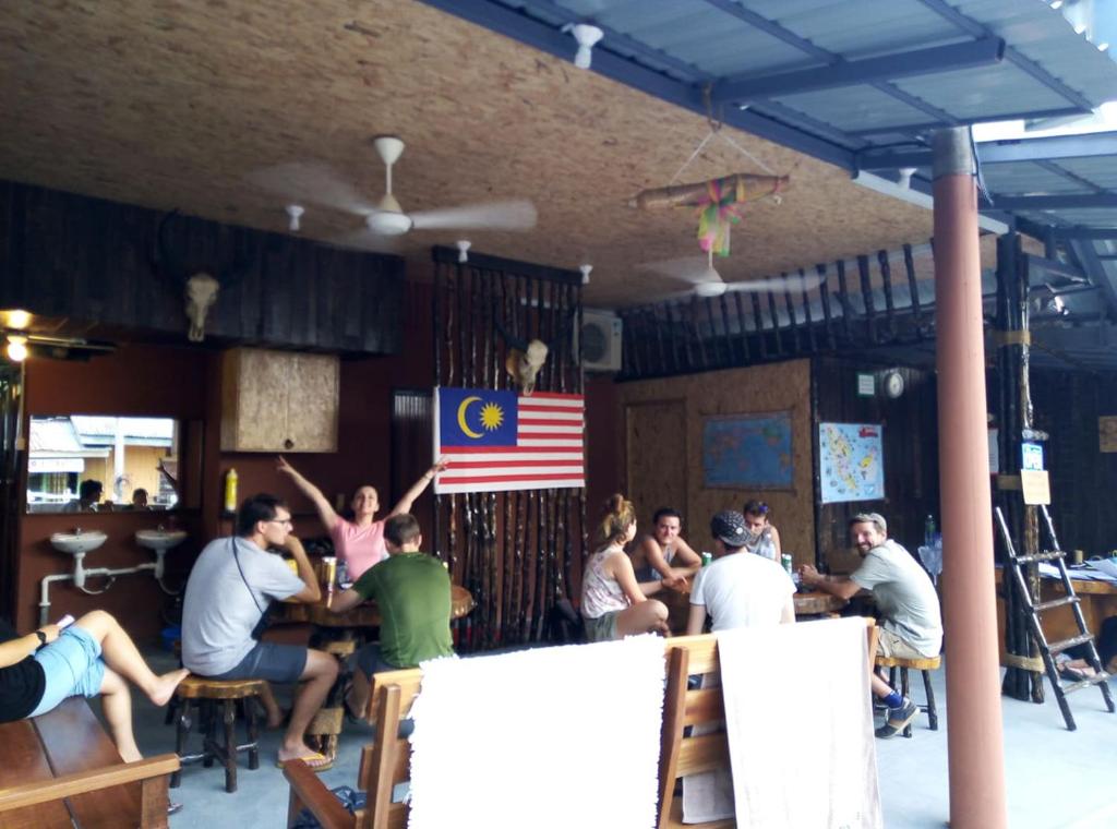 un grupo de personas sentadas en un bar en Agosto Taman Negara Hostel, en Kuala Tahan