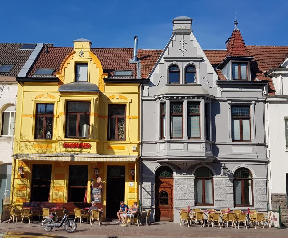 a yellow and white building with tables and chairs at Bed and Breakfast Allure in Vaals