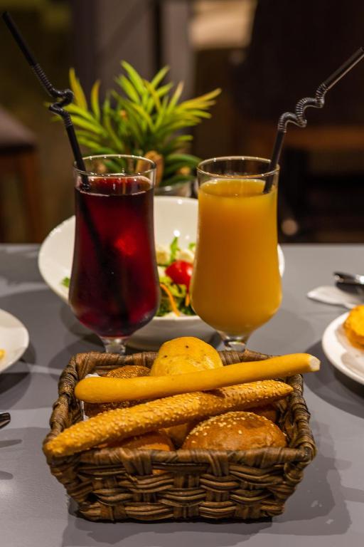 a table with a basket of food and two glasses of juice at Aksent Hotel in Baku