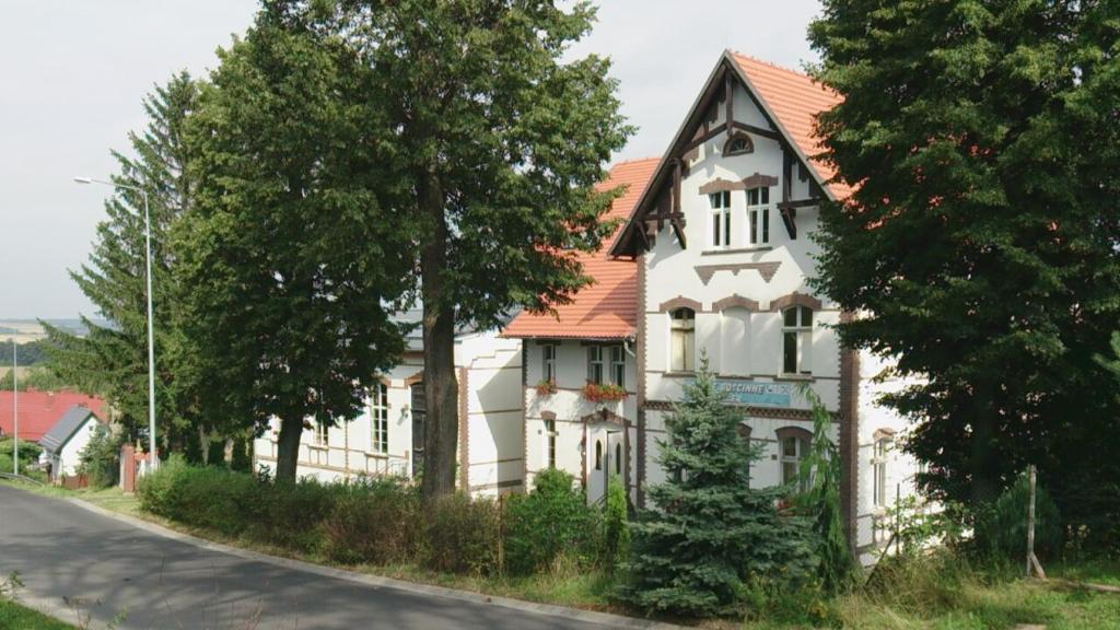 ein weißes Haus mit orangefarbenem Dach auf einer Straße in der Unterkunft Dom pod Orlimi Skałami in Leśna