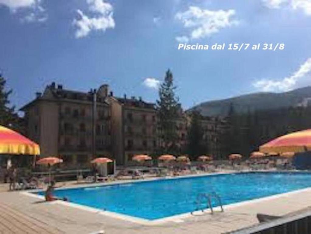 una grande piscina con sedie e ombrelloni di RESIDENCE ALTAIR Via Roma 13 a Ovindoli