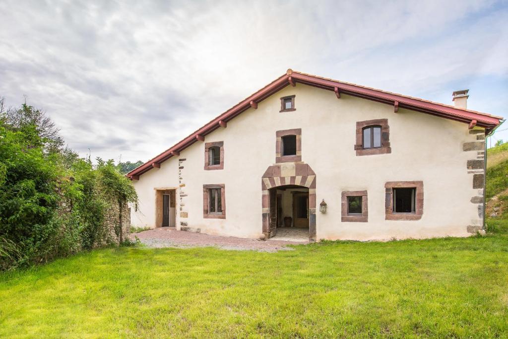 une grande maison blanche avec une cour en herbe dans l'établissement joangi, à Uhart-Cize