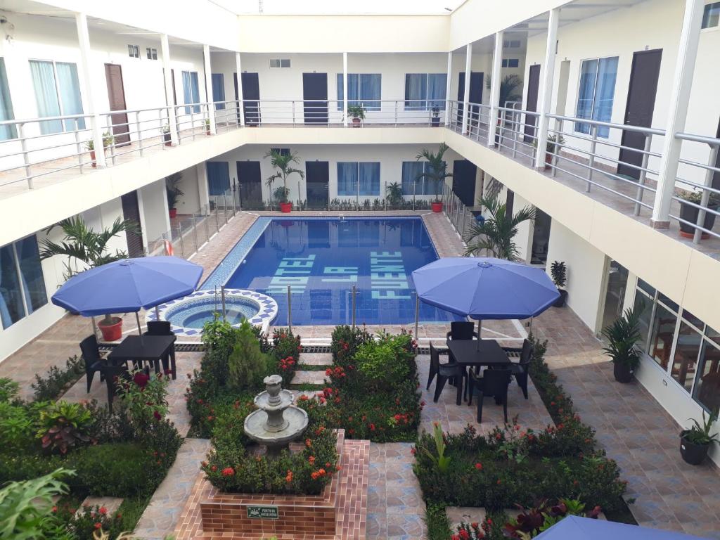 een patio met een zwembad en blauwe parasols bij Hotel la fuente j.n in La Macarena