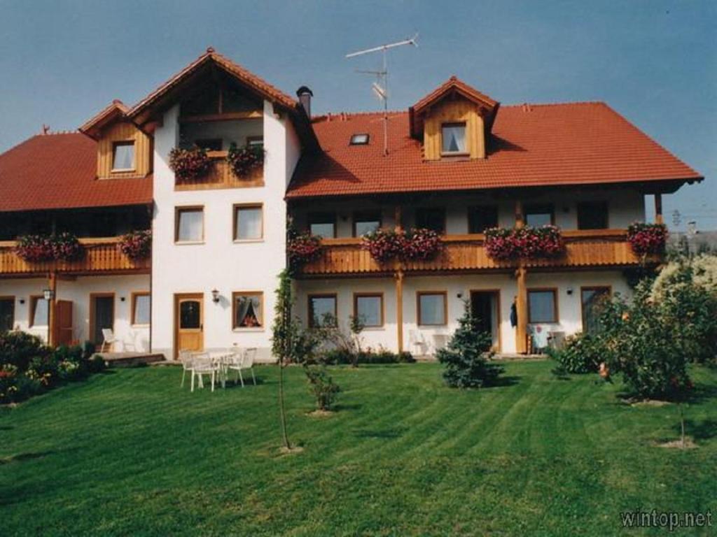 una casa grande con un patio verde delante de ella en Appartementhaus "Haflinger Hof", en Bad Füssing