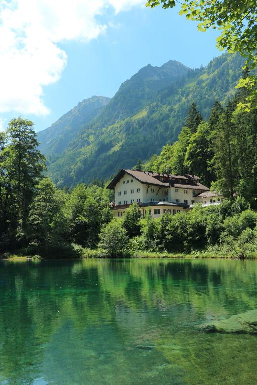 uma casa ao lado de um lago com montanhas em Elements Hotel Christlessee em Oberstdorf