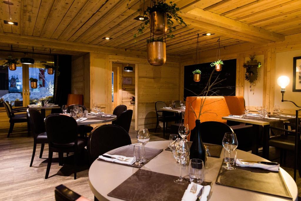 a restaurant with tables and chairs with wine glasses at Chalet-Hôtel La Marmotte, La Tapiaz &amp; SPA, The Originals Relais (Hotel-Chalet de Tradition) in Les Gets