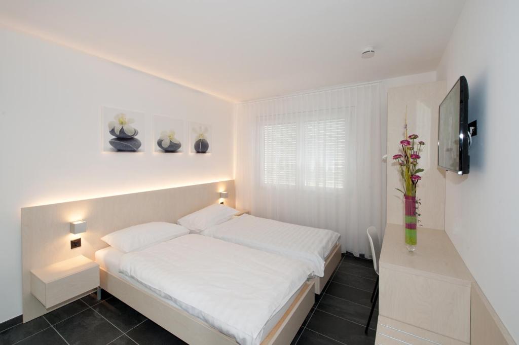 卡莫日諾的住宿－Hotel Morobbia，卧室配有白色的床和电视。