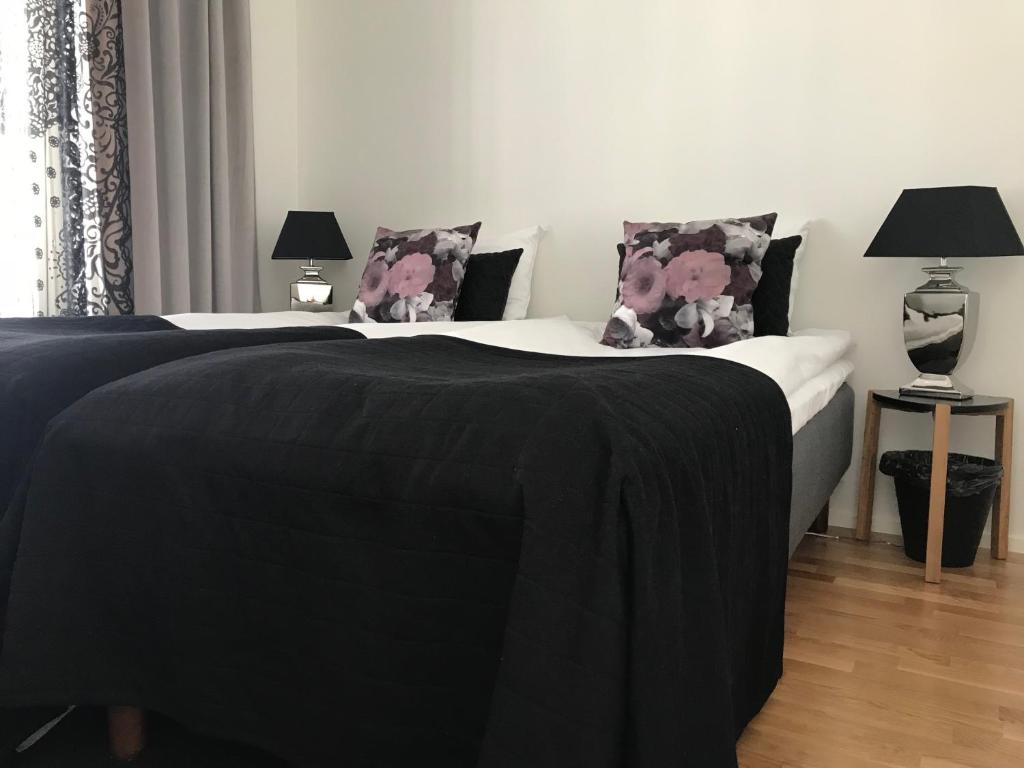 a bedroom with two beds with black blankets and pillows at Antintorni Suite 17 in Pori