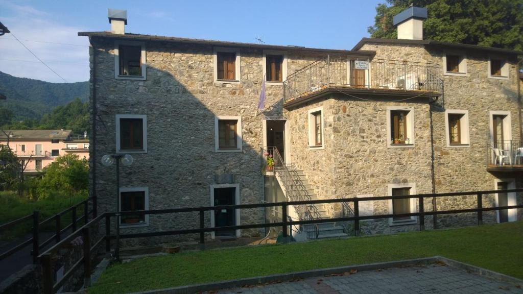 a large stone building with a staircase in front of it at Locanda Nonno Puin in Ferrada di Moconesi