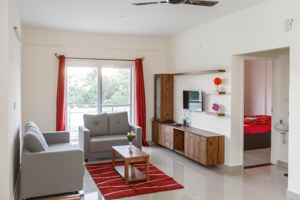 a living room with a couch chair and a television at Mistyblue Serviced Apartments in Bangalore