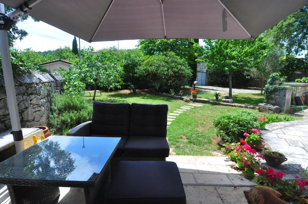 eine Terrasse mit einem Tisch, 2 Stühlen und einem Sonnenschirm in der Unterkunft Alla Cantina in Aurisina Case
