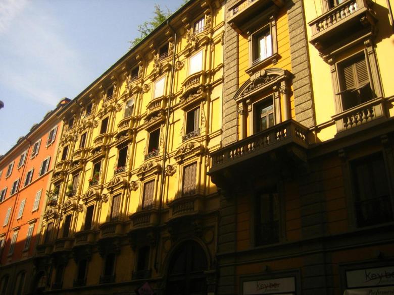 a large yellow building with windows and a balcony at Castaldi house in Milan