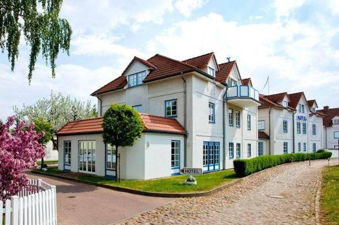 a large white house with red roof at Hotel Ingeborg in Waren