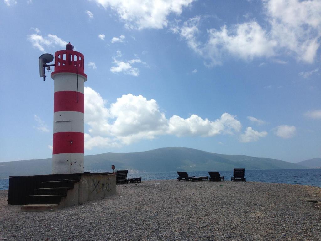 a red and white lighthouse on a beach with chairs at Private rooms - Tivat in Tivat