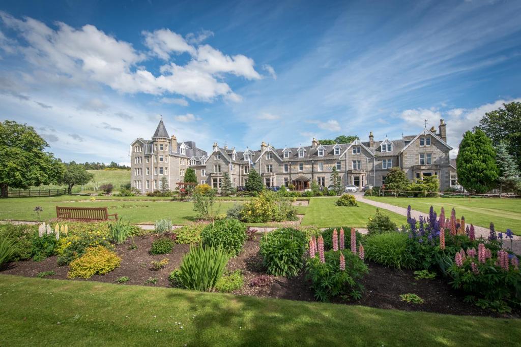 ein großes Herrenhaus mit Garten im Vordergrund in der Unterkunft Nethybridge Hotel in Nethy Bridge