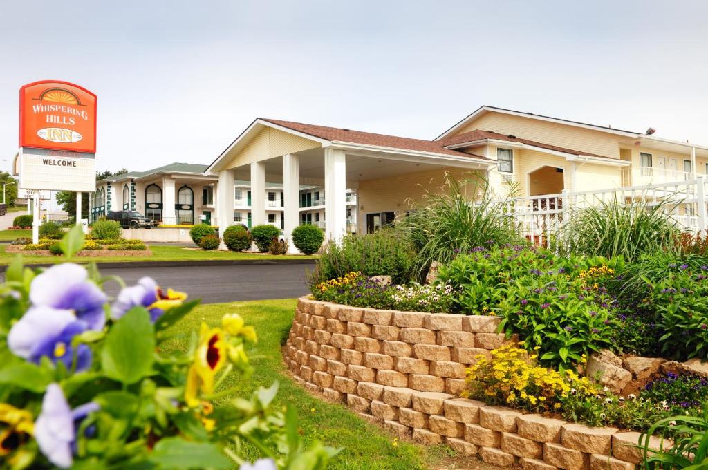 a house with a retaining wall and flowers in front of it at Whispering Hills Inn in Branson