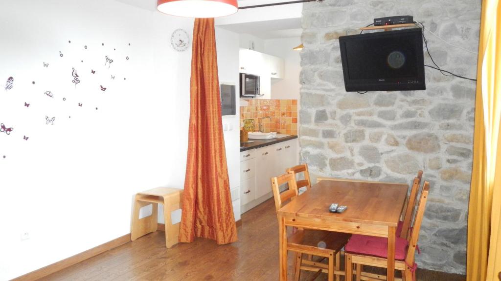 a kitchen with a table and a tv on a stone wall at Station de montclar in Saint-Jean
