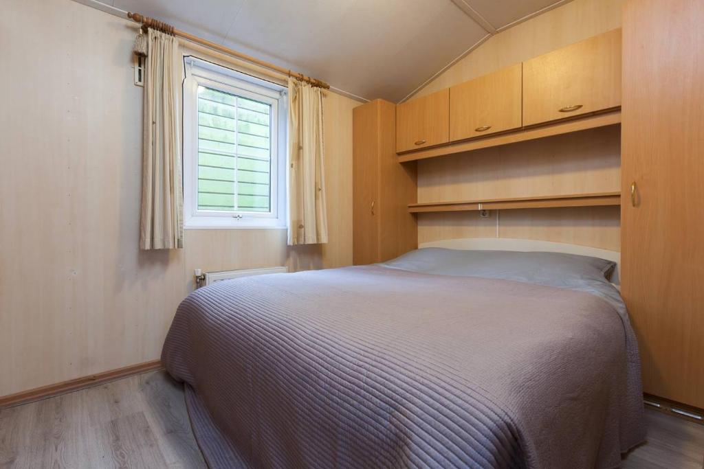 um quarto com uma cama grande e uma janela em Vakantie veluwe em Wageningen