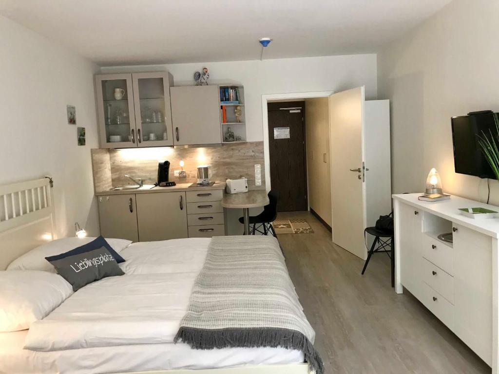 Cet appartement comprend une chambre avec un grand lit blanc et une cuisine. dans l'établissement Appartement Gluecks_Momente, à Glücksburg