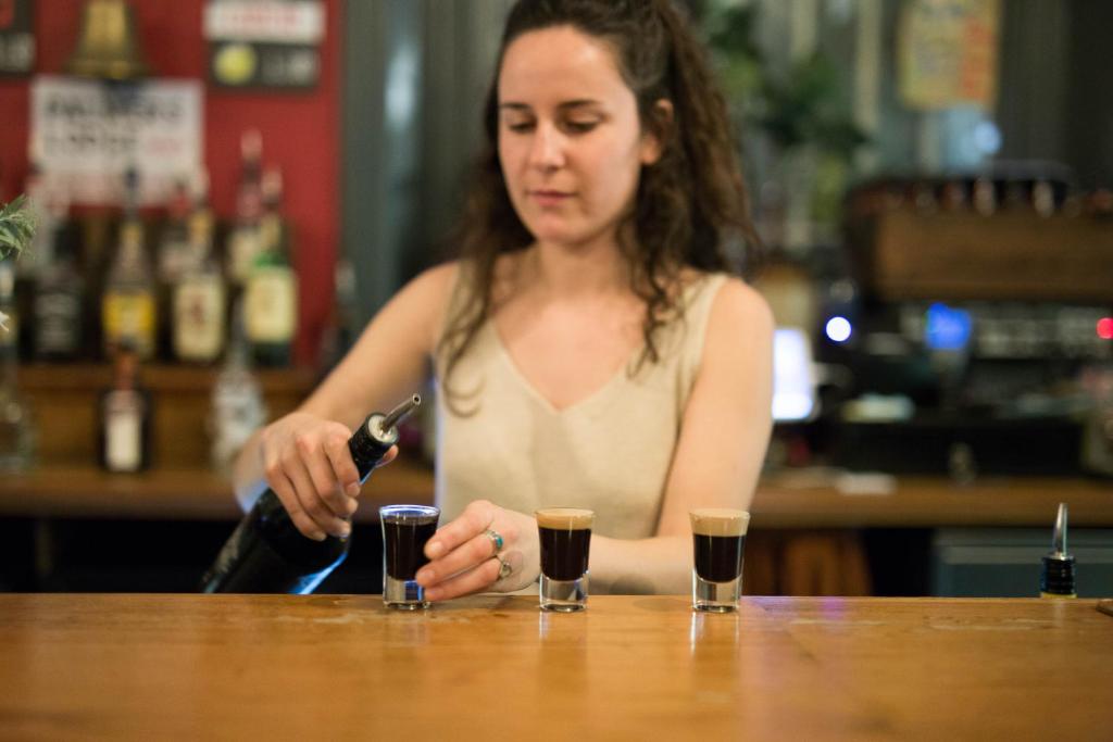 a woman sitting at a bar with two cups at Palmers Lodge Swiss Cottage in London