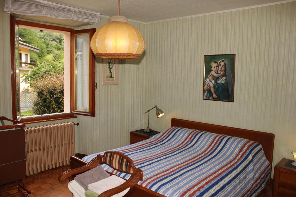 a bedroom with a bed and a lamp and a window at La casa rosa in Sernio