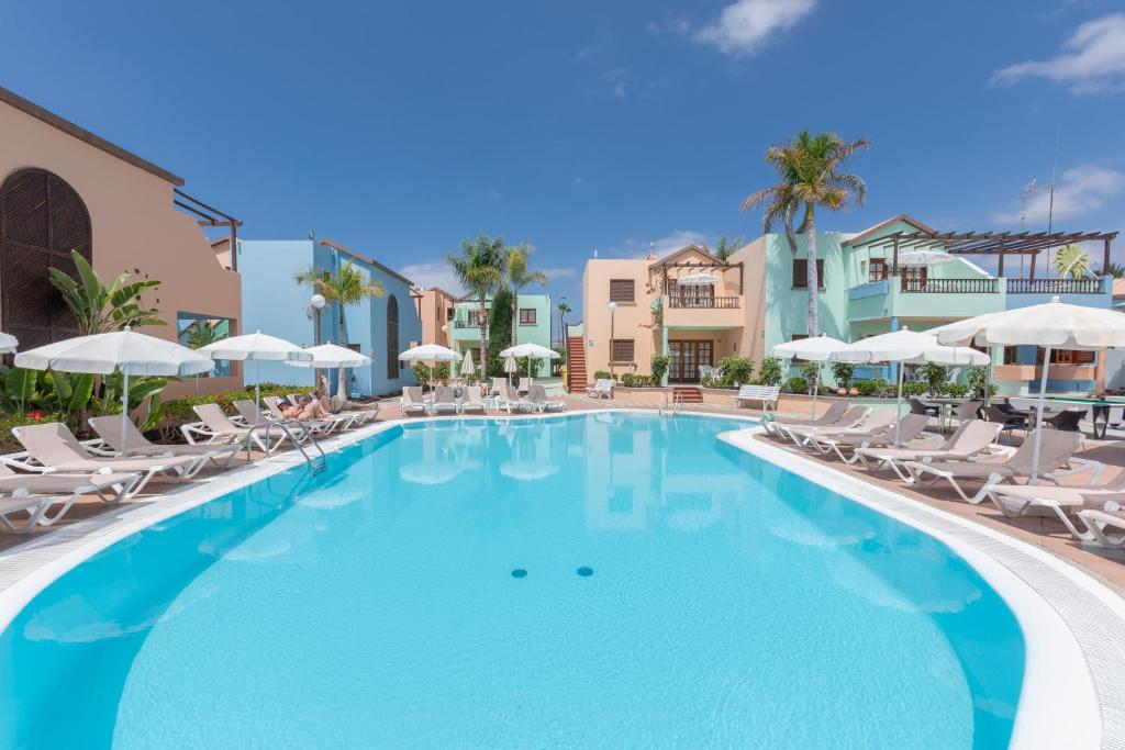 ein großer Pool mit Stühlen und Sonnenschirmen in der Unterkunft Club Vista Serena in Maspalomas