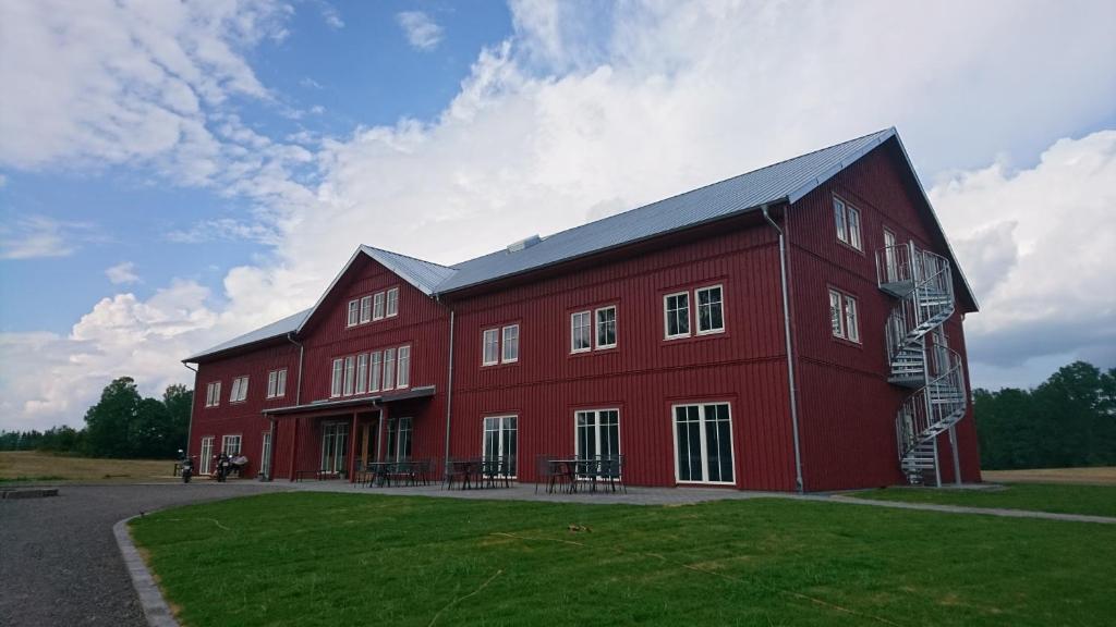 a large red barn with a black roof at Tiraholms hotell in Unnaryd