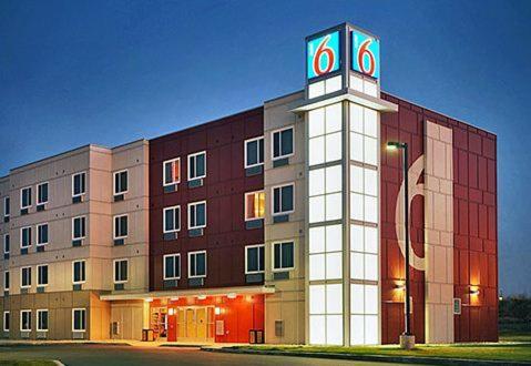 a building with a clock tower in front of it at Motel 6-Swift Current, SK in Swift Current