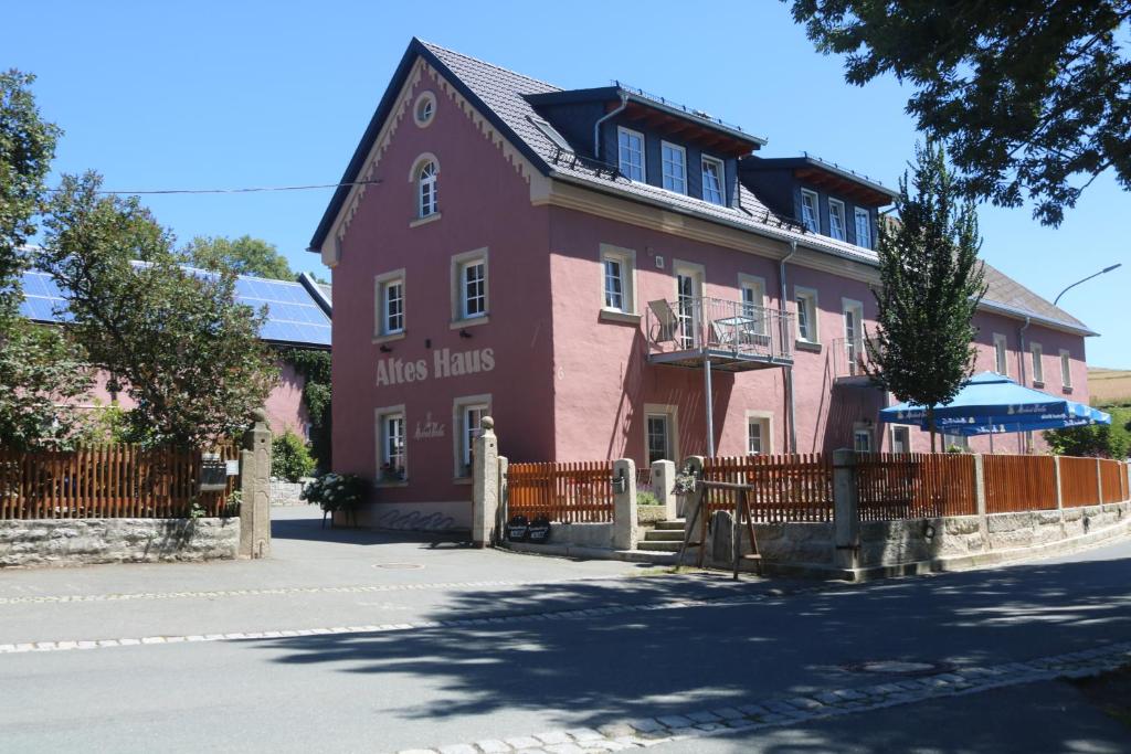 un bâtiment rose avec une clôture devant lui dans l'établissement Altes -Haus, à Gattendorf