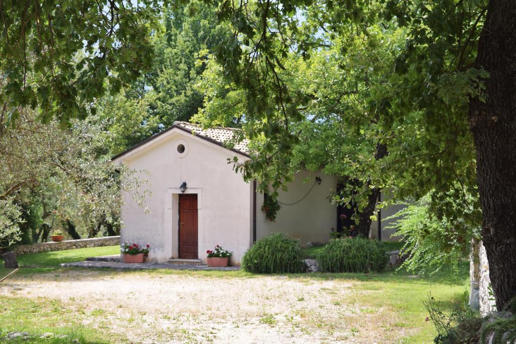 mały biały dom na podwórku z drzewami w obiekcie Antica Tenuta w mieście Balsorano Nuovo