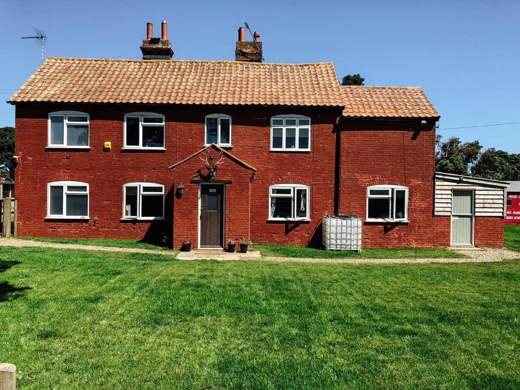 a large red brick house with a grass yard at The Lodge in Walberswick