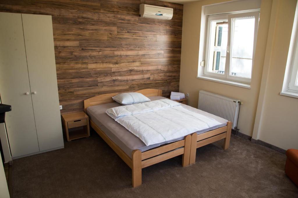 a bedroom with a bed and a wooden wall at Vege & Vegan Restaurant and Accommodation in Novi Sad