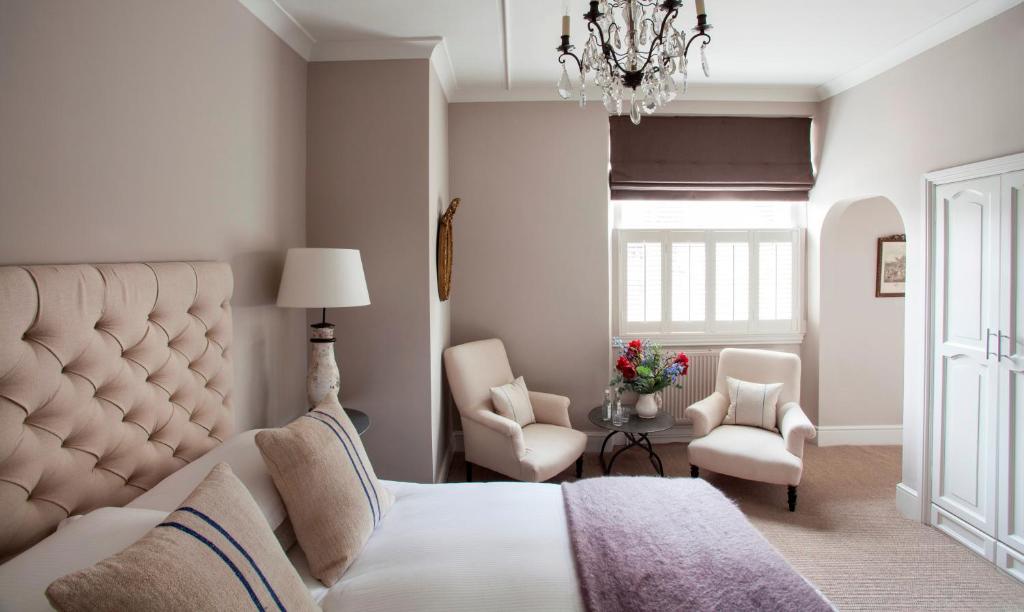 a bedroom with a bed and two chairs and a chandelier at The Lion Inn in Winchcombe